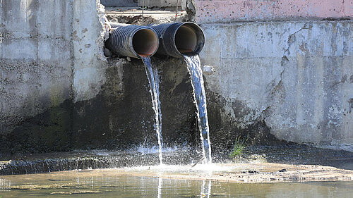 Dirty water pouring from pipe into water course